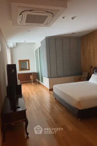 Spacious bedroom with modern decor and wooden flooring