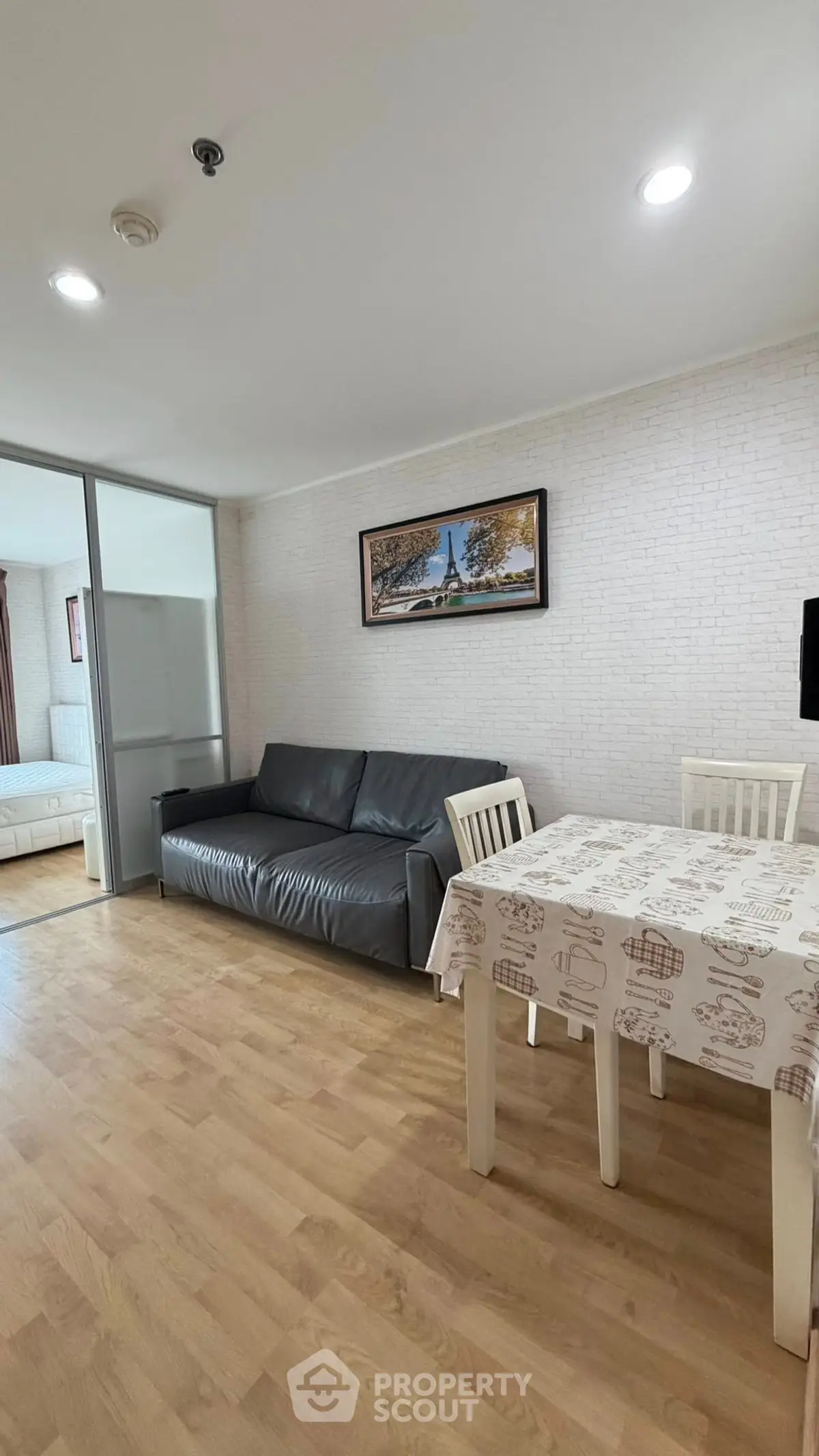 Modern living room with wooden flooring, cozy sofa, and dining area in open layout apartment.