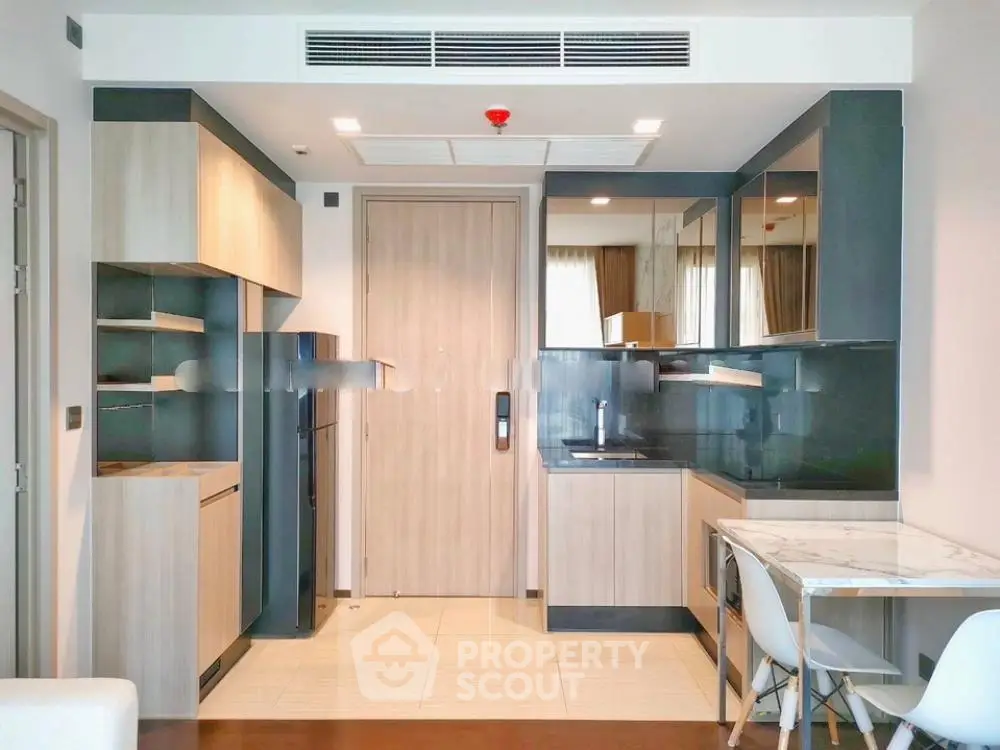 Modern kitchen with sleek cabinetry and dining area in a stylish apartment.