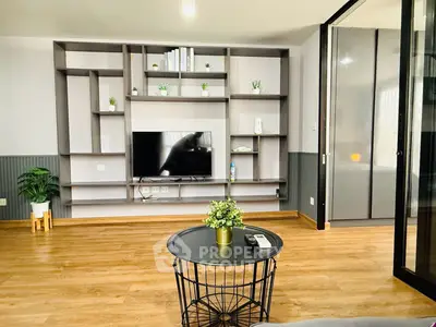 Modern living room with stylish shelving and TV, featuring wooden flooring and elegant decor.