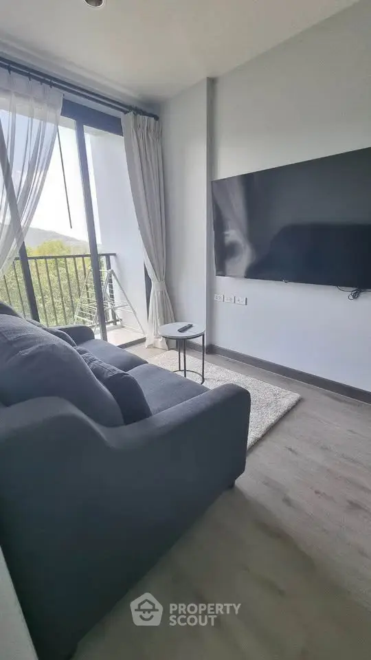 Modern living room with large TV and balcony view