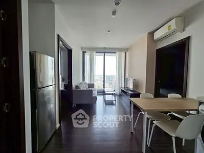 Modern apartment interior with open living and dining area, featuring large windows and sleek furniture.