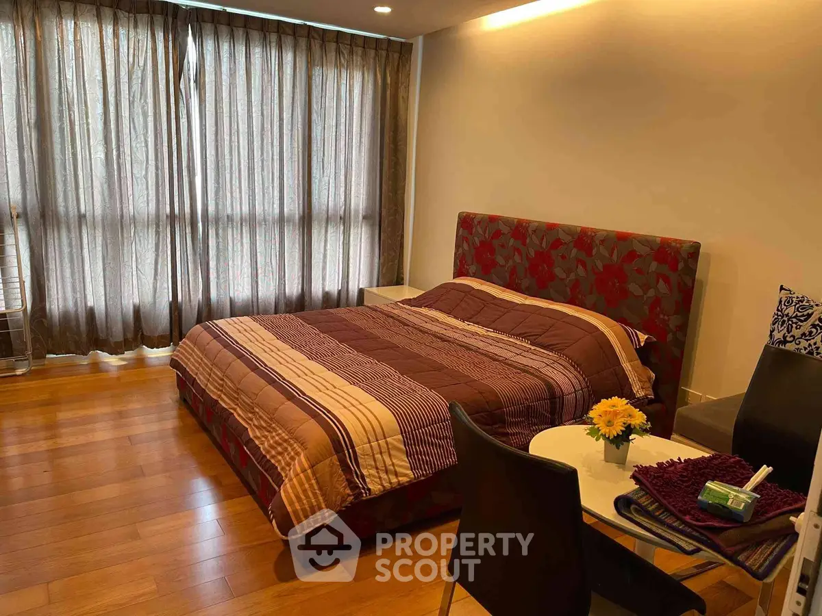 Spacious bedroom with elegant decor and natural light in modern apartment.