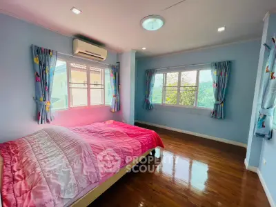 Spacious bedroom with large windows and wooden flooring in a cozy home.