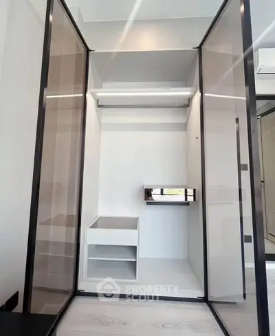 Modern walk-in closet with sleek glass doors and built-in shelving