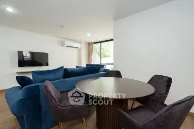 Modern living room with stylish blue sofa and round dining table, perfect for entertaining.