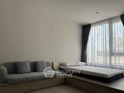 Modern minimalist bedroom with large window and cozy seating area