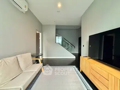 Modern living room with sleek design, featuring a large TV, stylish sofa, and elegant wooden furniture.
