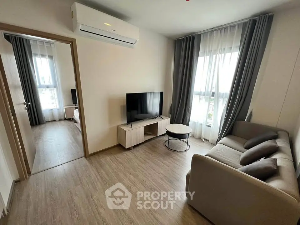 Modern living room with sleek furniture and natural light, featuring a cozy sofa and flat-screen TV.