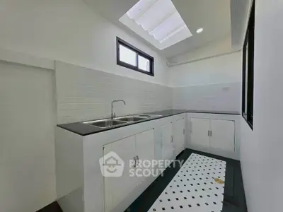 Modern kitchen with sleek white cabinets and skylight