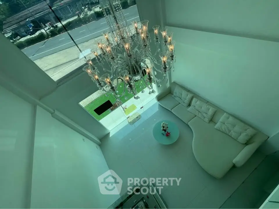 Luxurious high-ceiling living room with elegant chandelier and modern white sofa