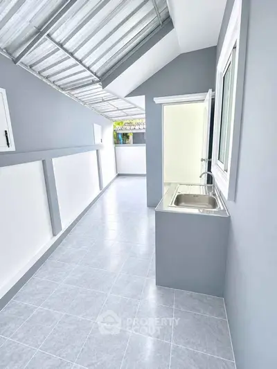 Modern outdoor kitchen with sleek design and stainless steel sink in a bright, airy space.