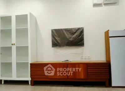 Modern living room with sleek wooden TV console and glass cabinet