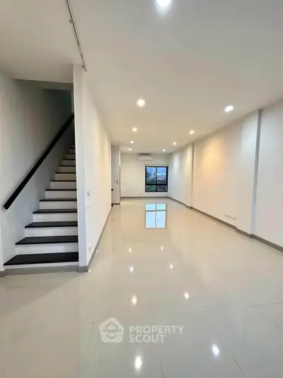 Spacious modern living room with sleek staircase and large window