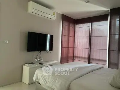 Modern bedroom with air conditioning and wall-mounted TV, featuring sleek design and natural light.