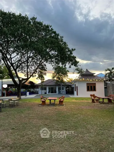 Charming garden view with cozy outdoor seating and picturesque houses at sunset.