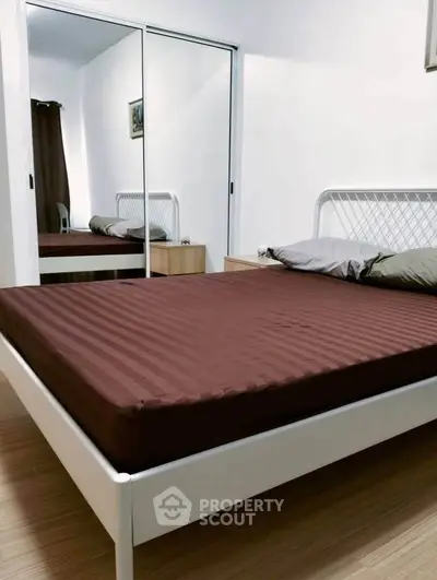Modern bedroom with mirrored closet and minimalist bed frame, perfect for cozy living.