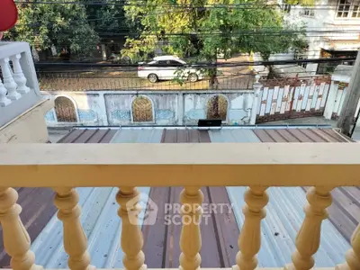 Charming balcony view overlooking a quiet street with lush greenery and classic architecture.