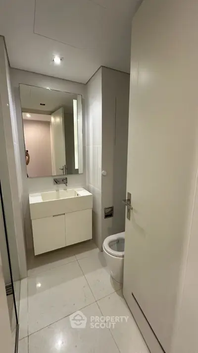 Modern minimalist bathroom with sleek white fixtures and large mirror
