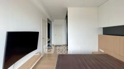 Modern bedroom with sleek design and wall-mounted TV, featuring minimalist decor.