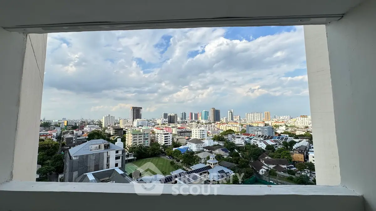 Stunning cityscape view from a high-rise window showcasing urban skyline and lush greenery.
