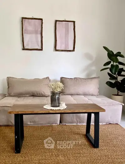 Cozy living room with beige sofa, wooden coffee table, and decorative plant, perfect for relaxation.