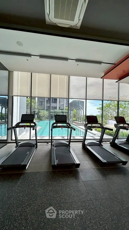 Modern gym with treadmills overlooking a luxurious pool and scenic view.