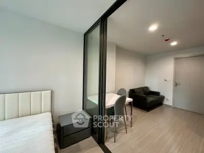 Modern studio apartment with sleek design and cozy furnishings, featuring a partitioned sleeping area and compact living space.