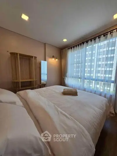 Spacious bedroom with large windows and modern decor in a high-rise apartment.