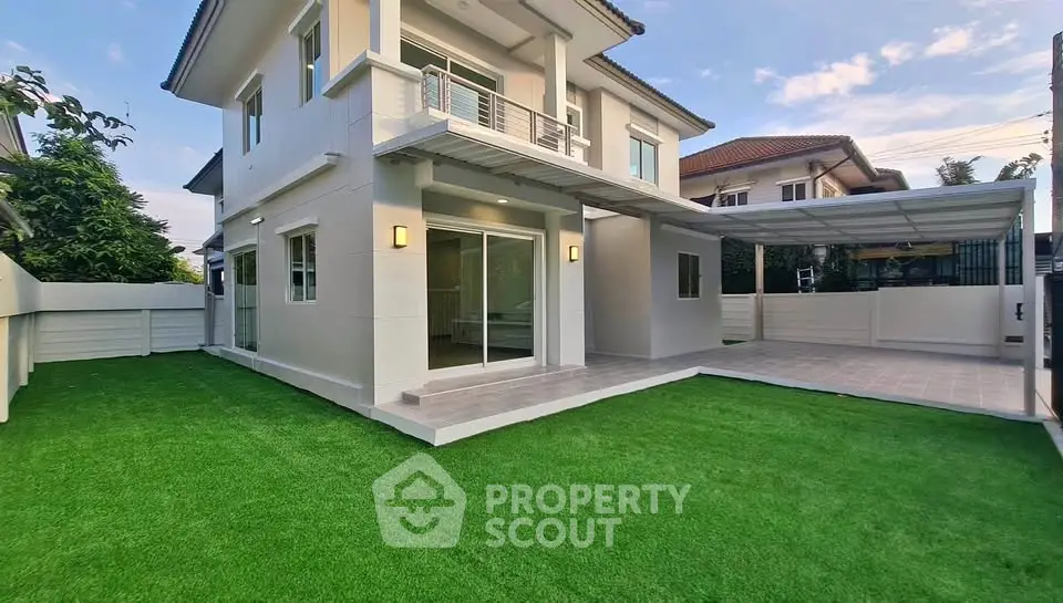 Modern two-story house with spacious lawn and covered parking area in a serene neighborhood.