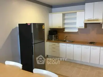 Modern kitchen with sleek cabinetry and stainless steel fridge in a cozy apartment.