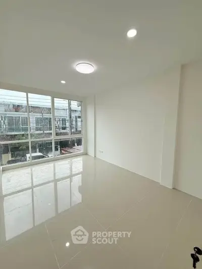 Spacious and bright living room with large windows and modern lighting in a contemporary home.