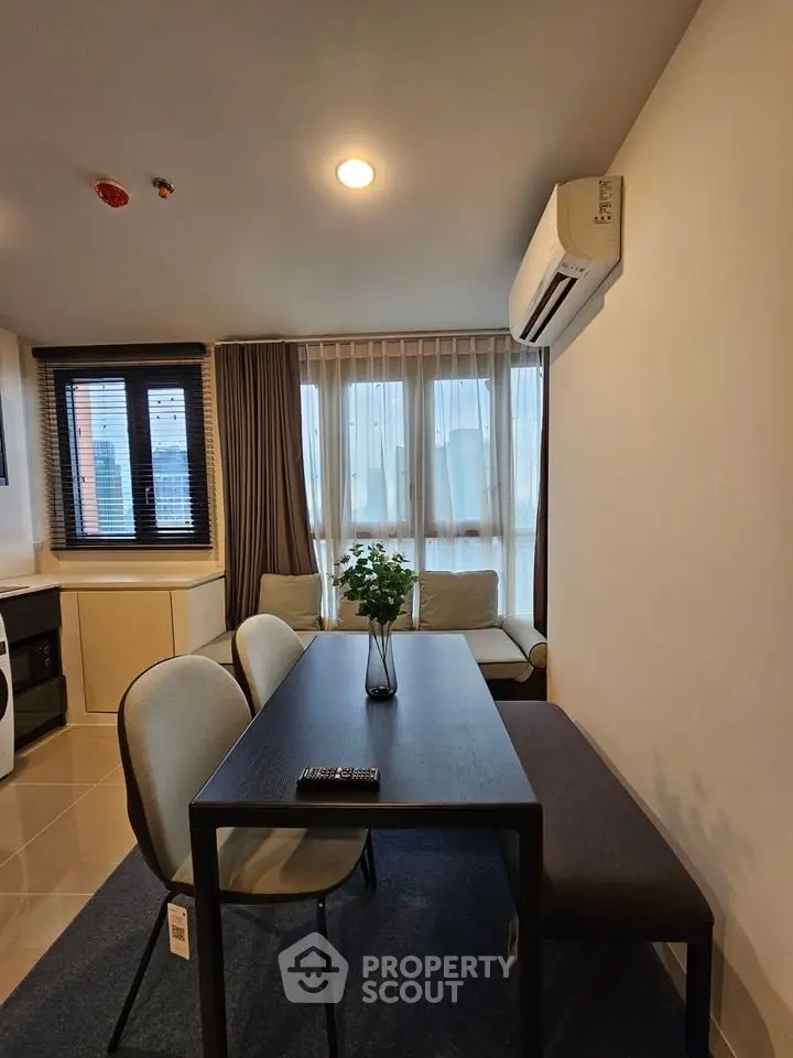 Modern dining area with sleek table and chairs, adjacent to cozy living space and large windows.