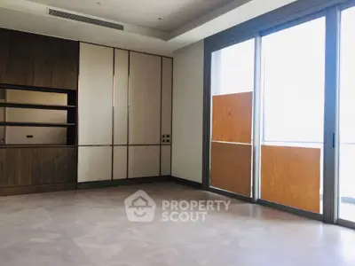 Spacious modern living room with large windows and built-in wooden shelving.