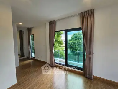 Spacious room with large windows and balcony overlooking lush greenery, perfect for serene living.