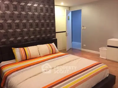 Modern bedroom with stylish wallpaper and cozy bedding in a contemporary apartment.