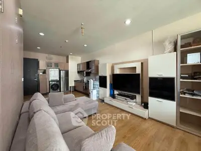 Modern living room with open kitchen, cozy sofa, and sleek appliances.