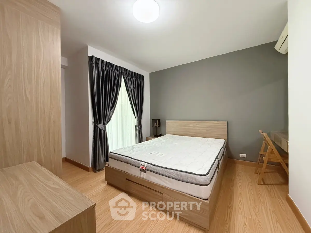 Modern bedroom with wooden flooring, stylish curtains, and a comfortable bed in a cozy apartment.