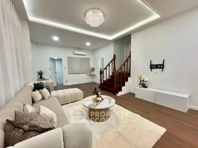 Spacious modern living room with elegant decor and staircase, featuring a plush sectional sofa and chic chandelier.