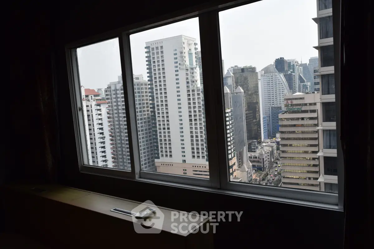 Stunning cityscape view from a high-rise apartment window, showcasing modern urban architecture.
