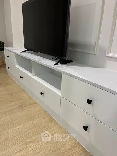 Modern living room with sleek white TV stand and flat-screen television.