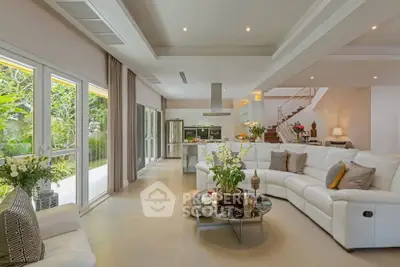 Luxurious open-plan living room with modern kitchen and garden view, featuring elegant decor and spacious seating.