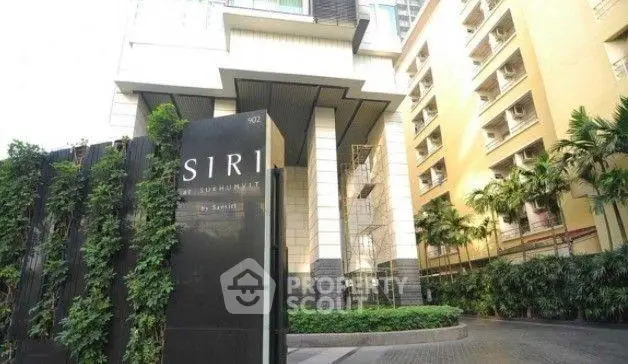 Luxurious condominium entrance with modern architecture and lush greenery.