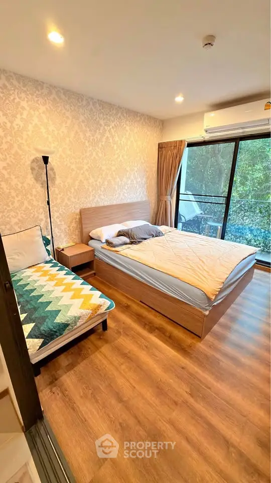 Spacious bedroom with modern decor and large window overlooking greenery, featuring cozy bed and stylish flooring.