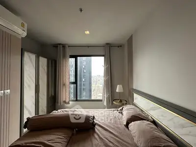 Modern bedroom with city view, featuring stylish decor and large window.