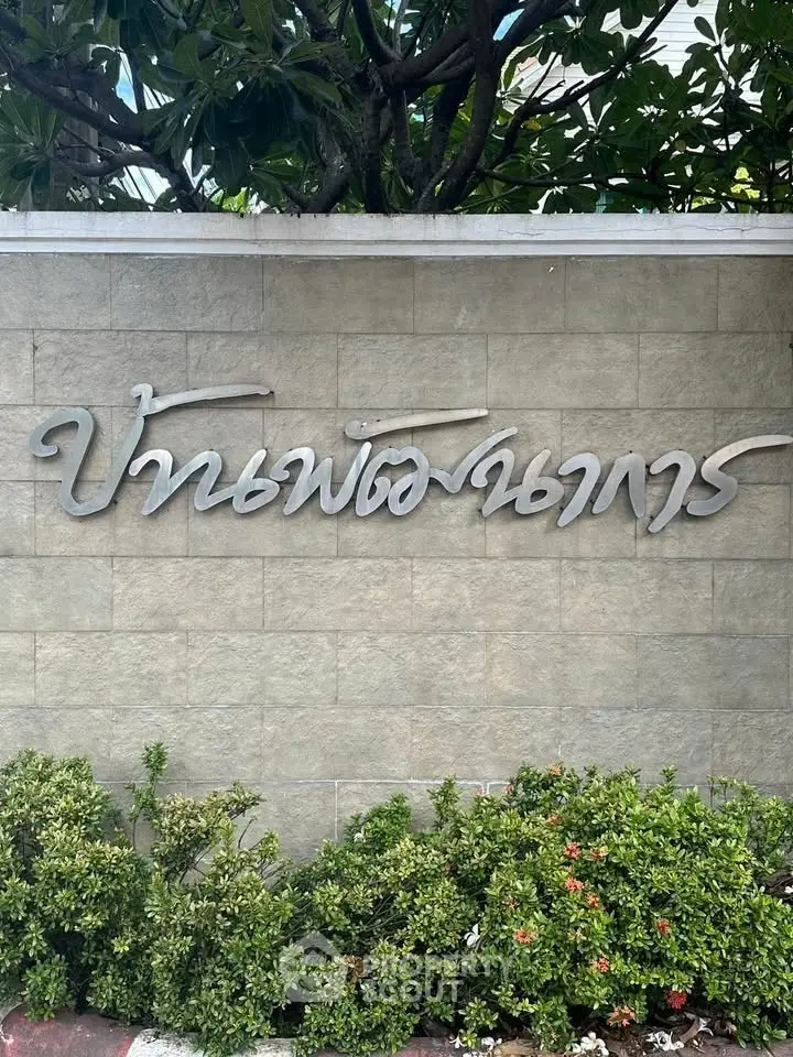 Elegant entrance sign with lush greenery at a prestigious property.