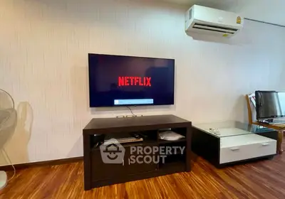 Modern living room with wall-mounted TV and air conditioning, featuring stylish wooden flooring.