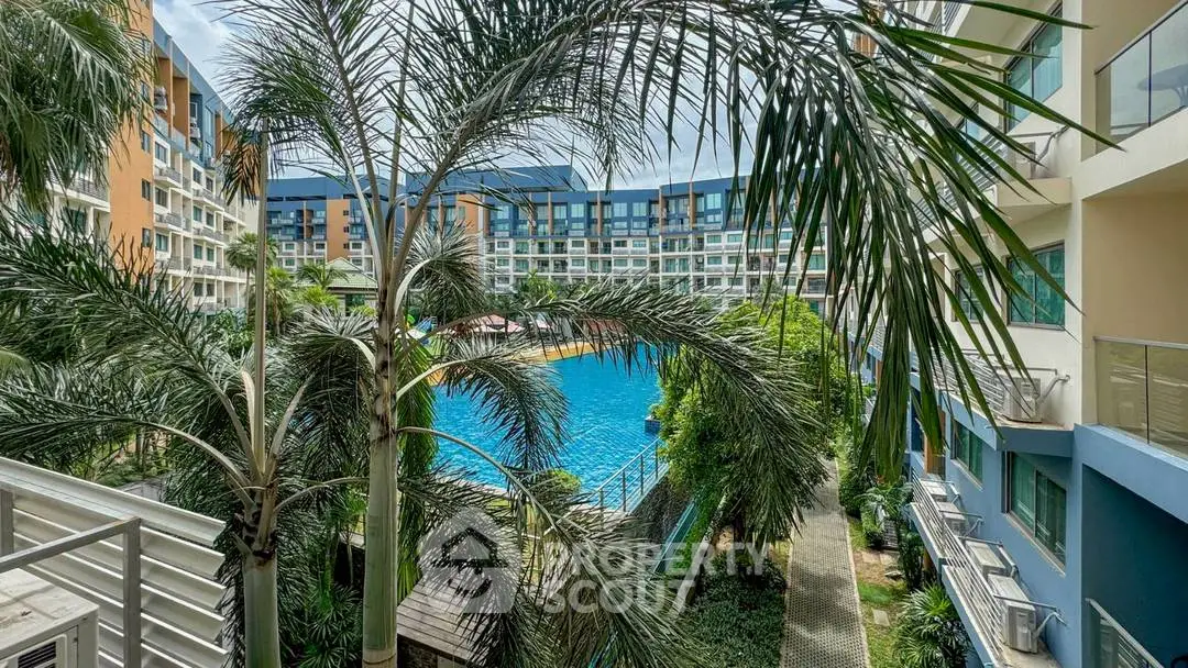 Stunning view of a modern apartment complex with a large pool and lush greenery.