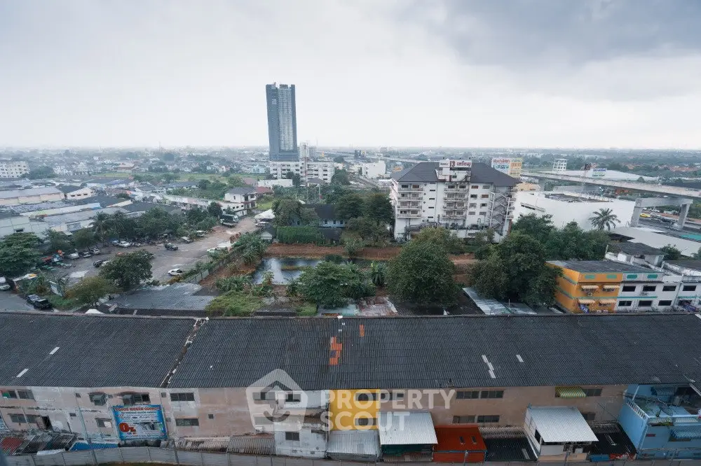 Panoramic view of urban landscape with residential and commercial buildings under cloudy sky.