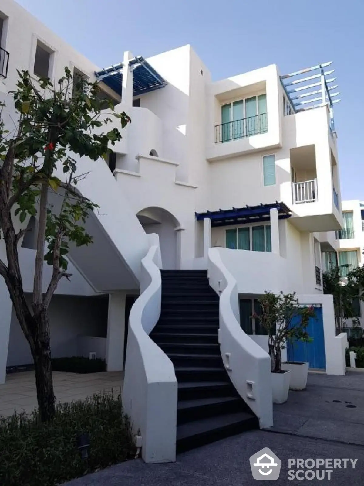 Modern white building with unique staircase and lush greenery